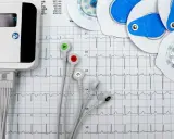 Elektrokardiograf i elektrody do badań serca na tle zapisu EKG.