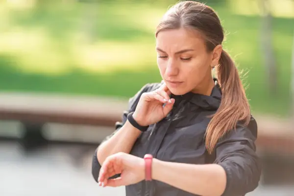 Kobieta sprawdza swój puls 85 na zegarku sportowym po treningu.